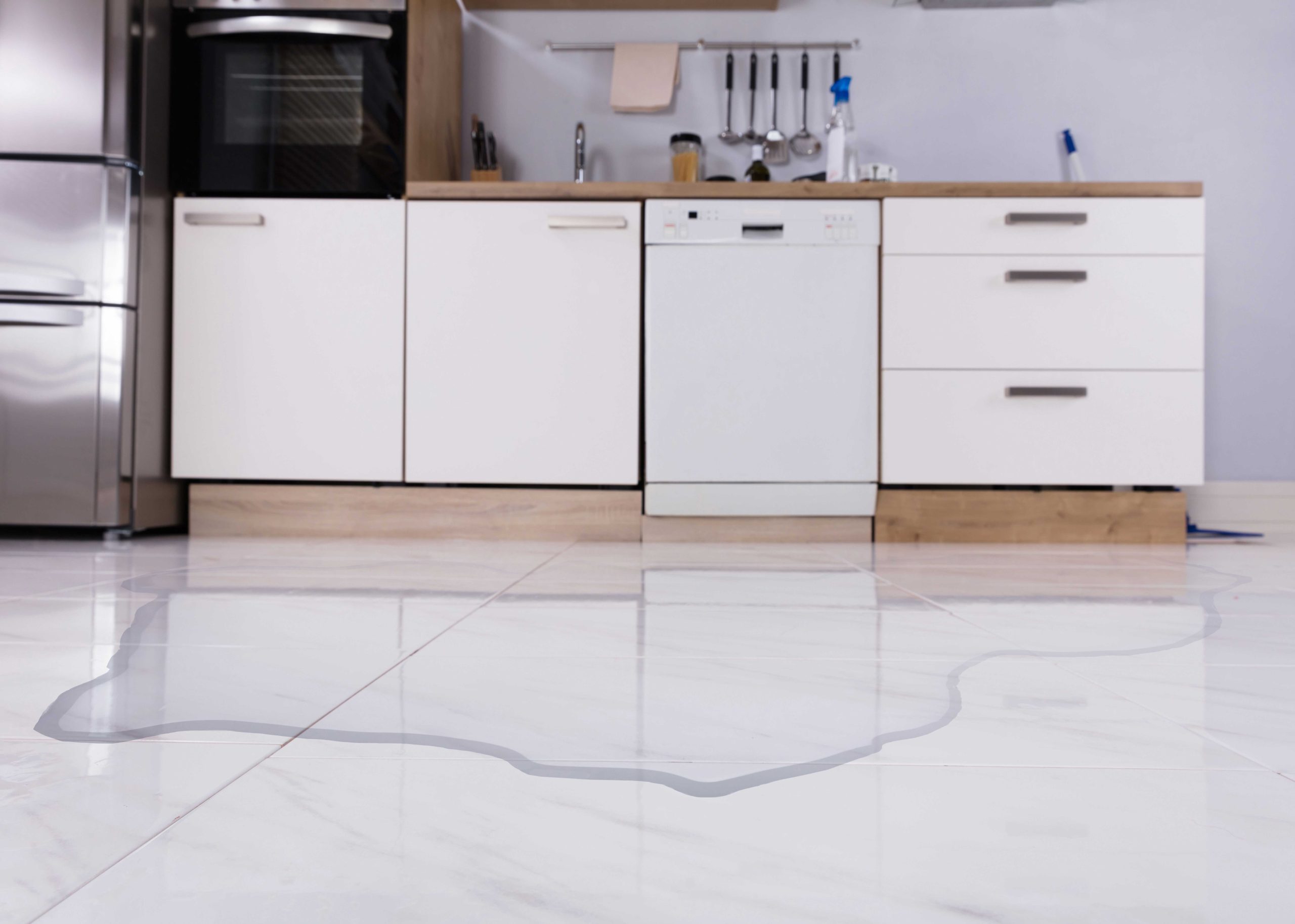 Standing water on a kitchen floor from a dishwasher leak in an Austin, TX home