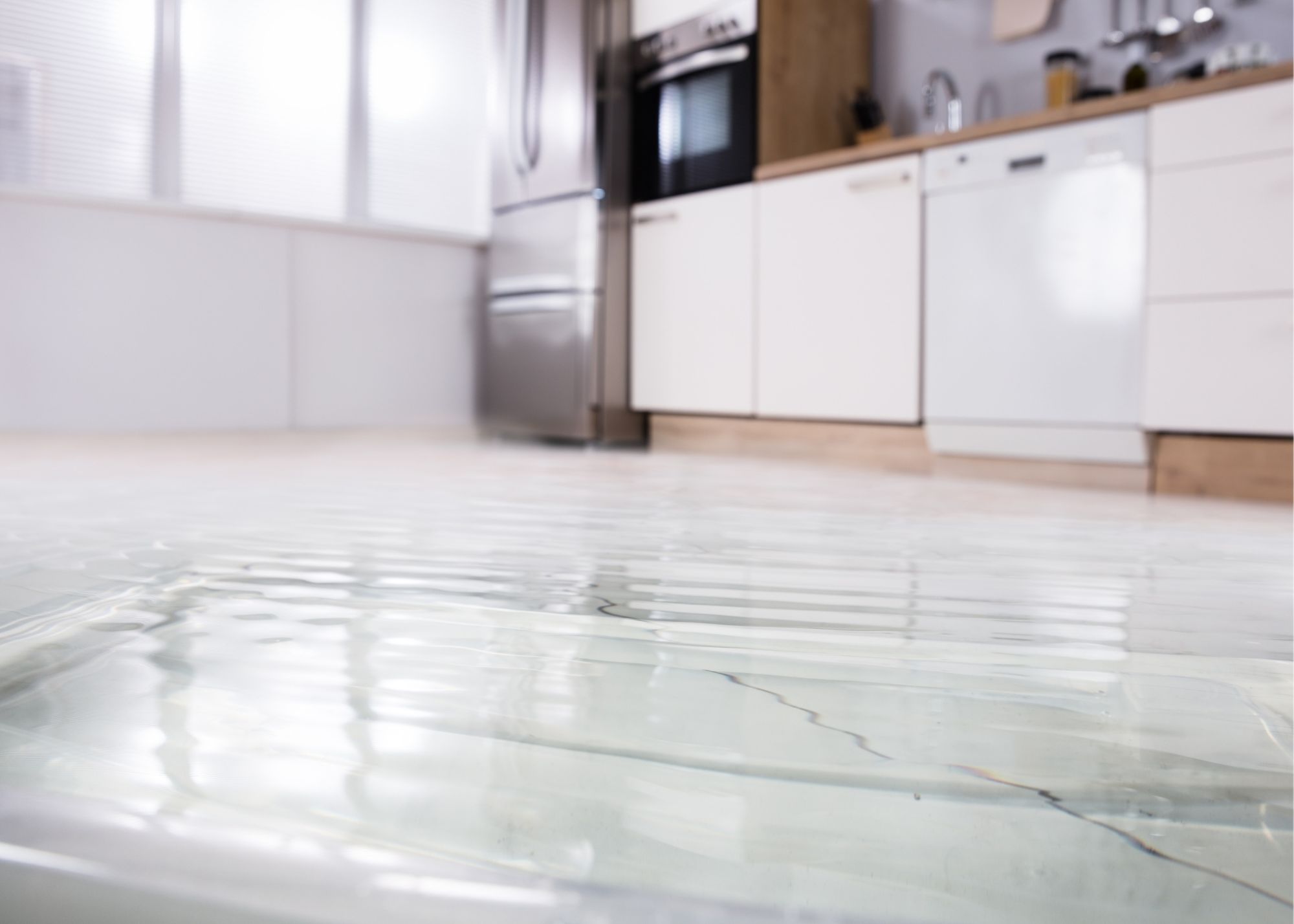 Standing water spreading across a kitchen floor in an Austin, TX home